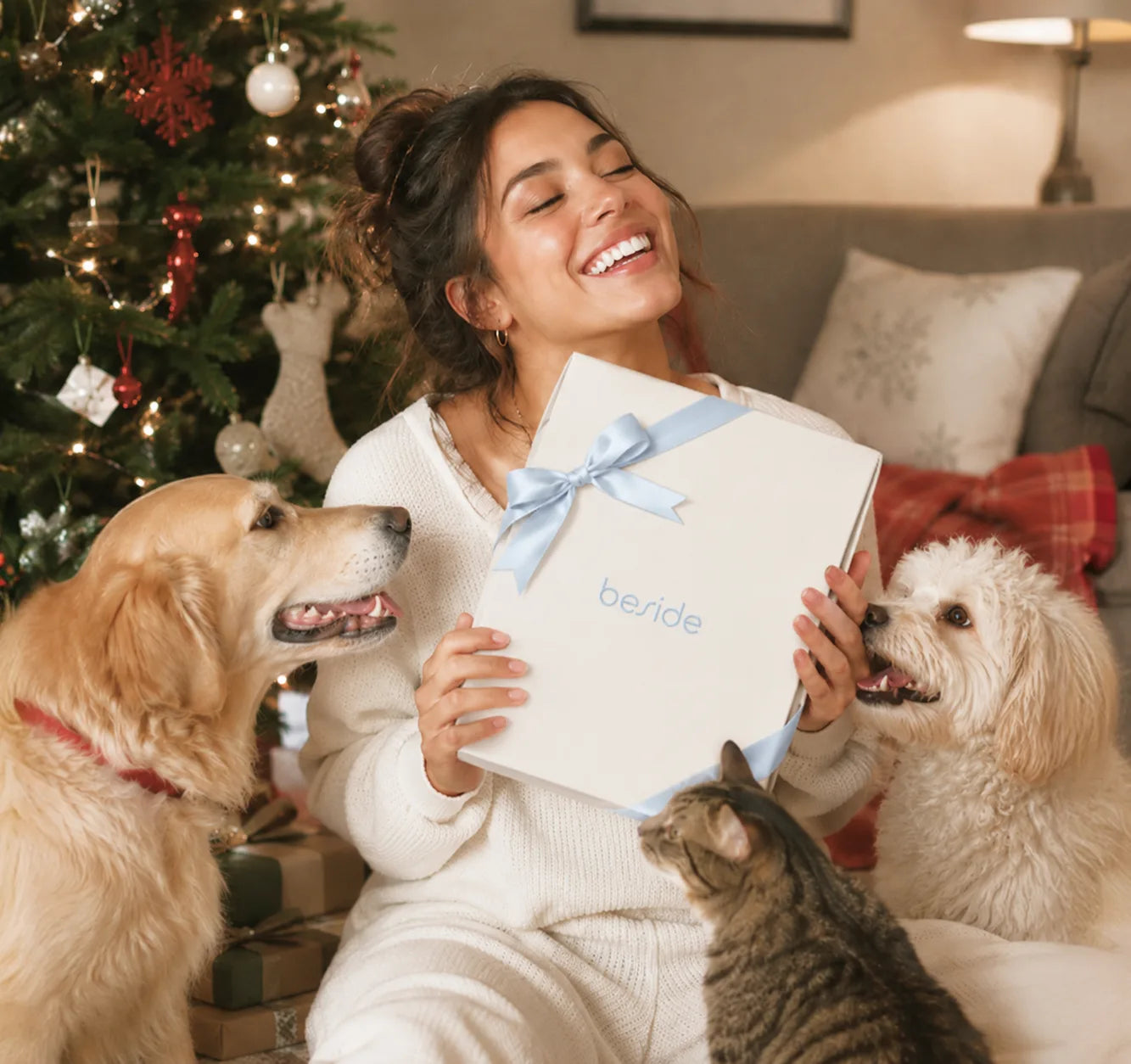 A woman hugging a Beside gift box, surrounded by dogs and a cat